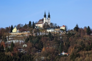 Basilika auf einem Hügel mit Wald im Winter, klarer blauer Himmel.