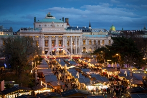 Weihnachtsmarkt vor einem beleuchteten historischen Gebäude am Abend.