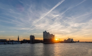 Elbphilharmonie und Hamburg-Skyline bei Sonnenuntergang am Fluss.
