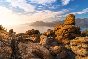 Blick auf felsige Küstenlandschaft mit Meer und bewölktem Himmel.