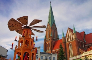 Weihnachtspyramide vor einer Kirche mit blauem Himmel.