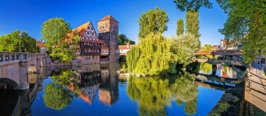 Flusslandschaft mit historischem Gebäude und Brücke, Spiegelung im Wasser.