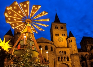Weihnachtspyramide vor einer beleuchteten Kirche bei Nacht.
