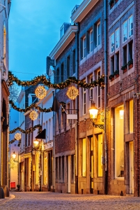 Gepflasterte Gasse mit Weihnachtsbeleuchtung in der Dämmerung.