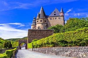 Mittelalterliches Schloss vor blauem Himmel und grüner Vegetation.