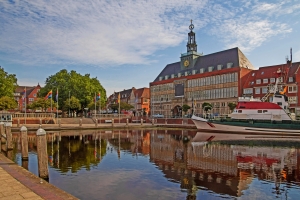 Rathaus mit historischem Hafen und Boot bei klarem Himmel.
