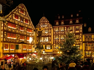 Fachwerkhäuser und Weihnachtsmarkt bei Nacht mit beleuchtetem Baum.