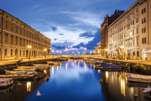 Kanal in einer Stadt bei Dämmerung, beleuchtet von Straßenlaternen.