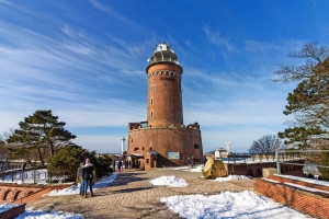 Ein roter Backsteinleuchtturm bei sonnigem Wetter mit Schnee auf dem Boden.