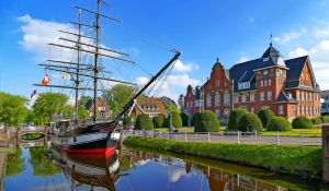Segelschiff im Hafen mit historischem Gebäude im Hintergrund.