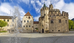 Historisches Schloss mit Burgturm und Innenhof bei sonnigem Himmel.